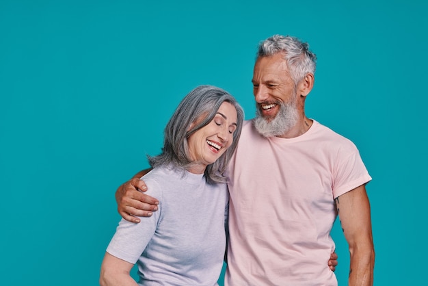 gelukkig senior paar glimlachen terwijl ze samen staan tegen een blauwe achtergrond