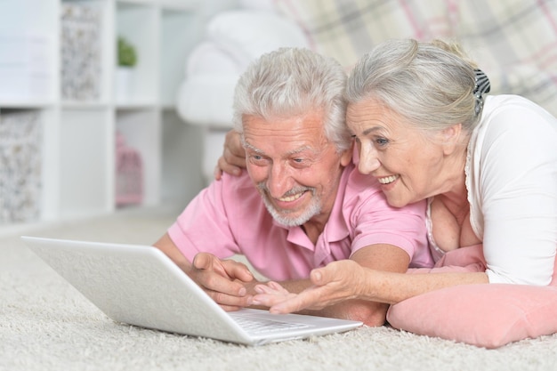 Gelukkig senior paar liggend op de vloer met moderne tablet