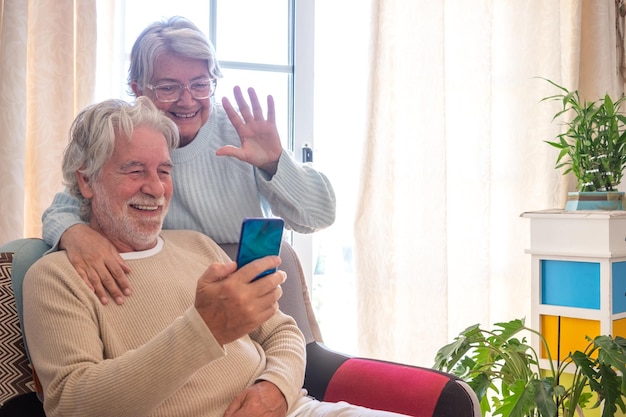 Gelukkig senior paar om thuis te zitten in videogesprek met smartphone