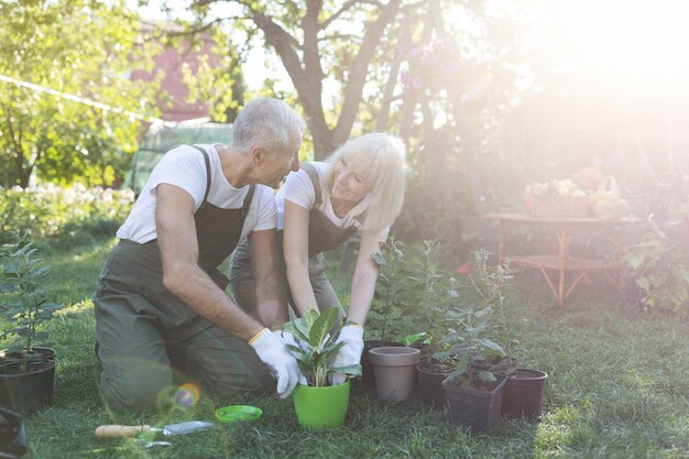 Gelukkig senior paar tuinieren en praten over planten uit potten op zonnige lentedag gratis