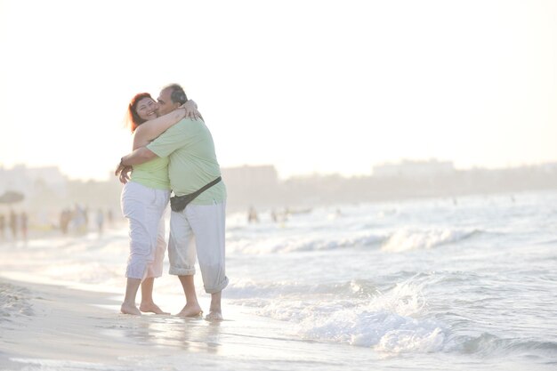 gelukkig senior volwassen bejaarde echtpaar heeft romantische tijd op het strand bij zonsondergang