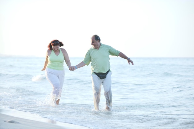 gelukkig senior volwassen bejaarde echtpaar heeft romantische tijd op het strand bij zonsondergang