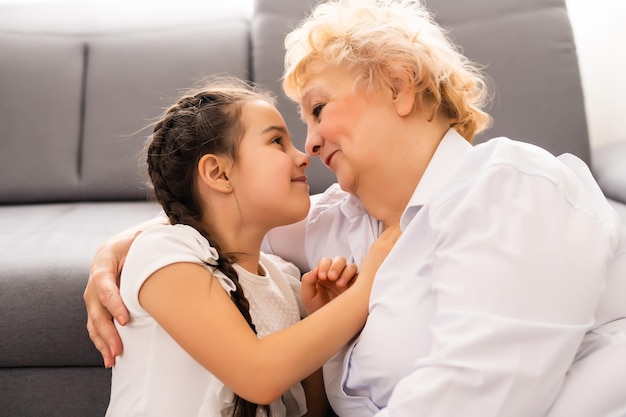 Gelukkig senior vrouw haar mooie kleinkind thuis knuffelen.