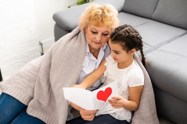 Gelukkig senior vrouw haar mooie kleinkind thuis knuffelen.