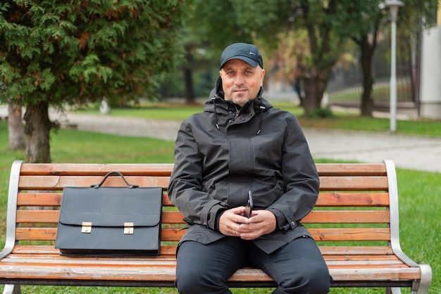 Gelukkig senior zakenman zittend op de bank in het park