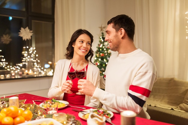 Gelukkig stel drinkt rode wijn bij het kerstdiner.