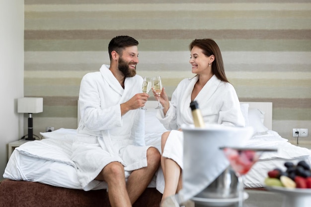 Gelukkig stel een man en een vrouw in een witte jas glimlachen naar elkaar en drinken mousserende wijn