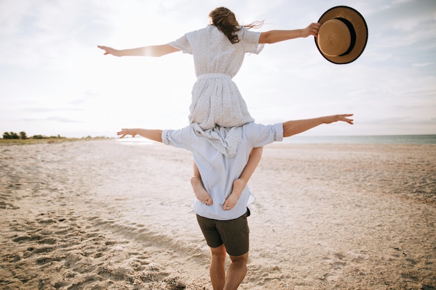 Gelukkig stel. jonge vrouw op de schouders van haar man op het strand. zomervakantie concept