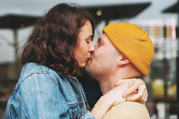 Gelukkig stijlvol jong familiepaar verliefd hipsters die plezier hebben tegen de glazen wand