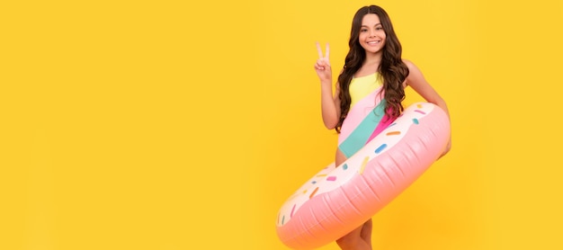 Gelukkig strand kind in zwembroek met donut opblaasbare ring op gele achtergrond zomer Banner van zomer kind meisje in zwembroek studio poster kop met kopie ruimte