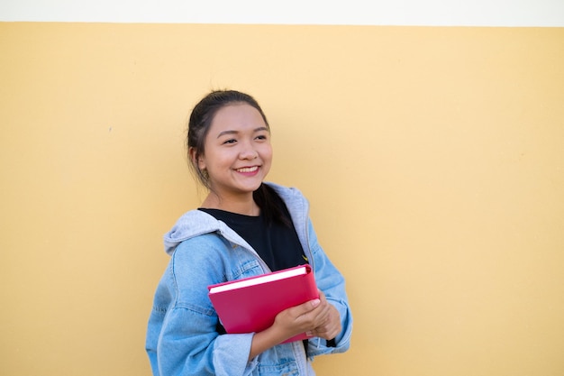 Gelukkig student jong meisje met roze boek op bruine achtergrond.