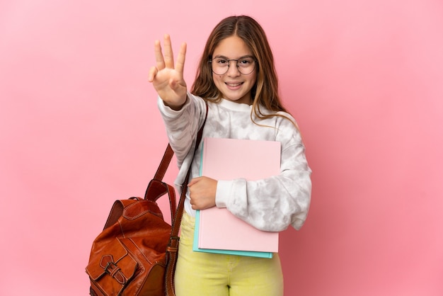 Gelukkig studentenmeisje over geïsoleerde roze muur die drie met vingers telt