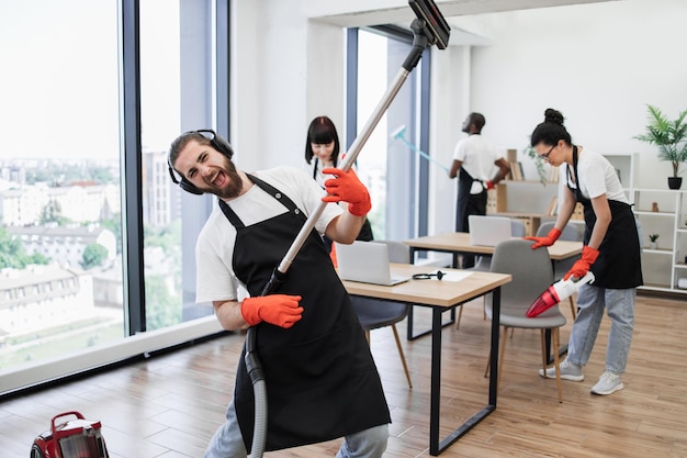 Foto gelukkig team van mensen in zwarte schorten schoonmaken modern kantoor