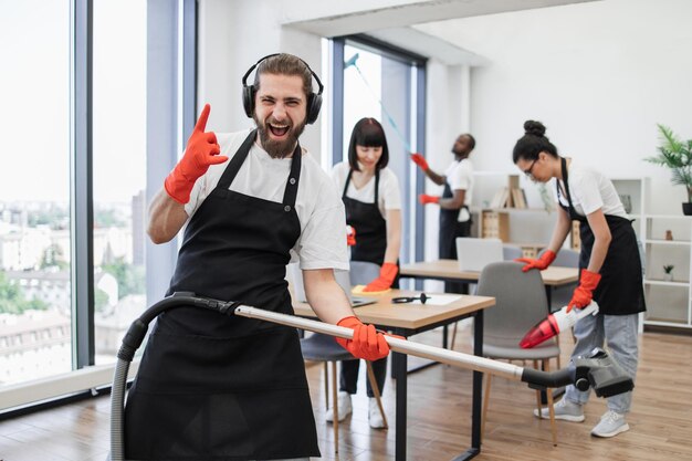 Foto gelukkig team van mensen in zwarte schorten schoonmaken modern kantoor