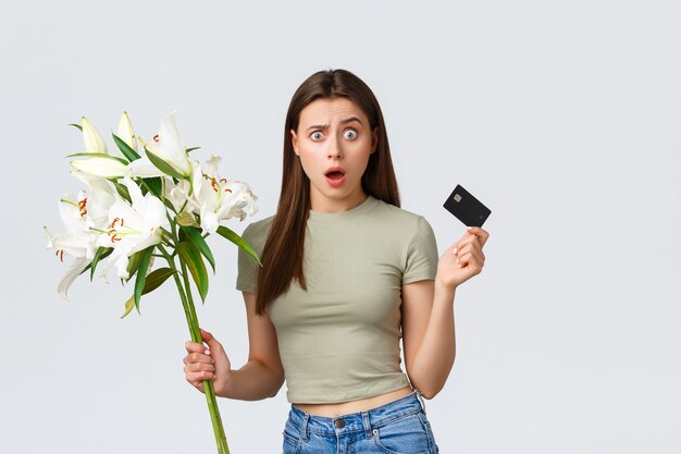 Gelukkig tedere jonge vrouw bestelde boeket bloemen levering met creditcard glimlachend tevreden en ho...