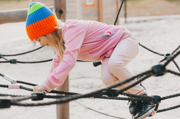 Gelukkig tiener meisje kind spelen in touw spinnenweb op speelplaats. sport voor kinderen.