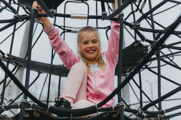 Gelukkig tiener meisje kind spelen in touw spinnenweb op speelplaats. sport voor kinderen.