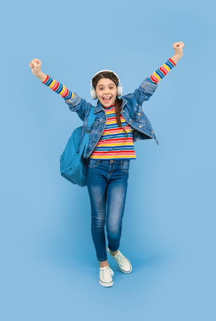 Gelukkig tienermeisje dat winnend gebaar maakt blauwe achtergrond school Muziekschool Terug naar school