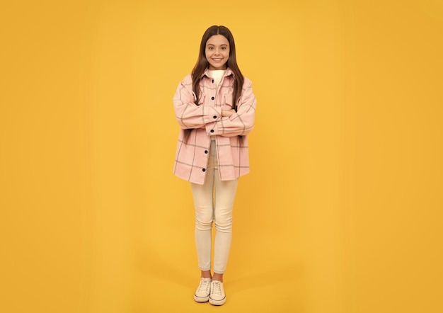 Gelukkig tienermeisje draagt een roze geruit overhemd, gekruiste handen casual
