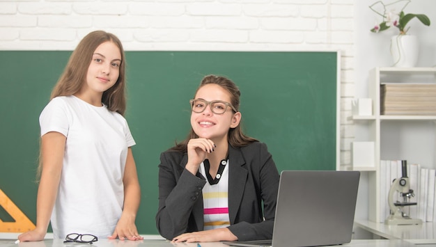 Gelukkig tienermeisje en tutor op schoolklas met computerlerarendag