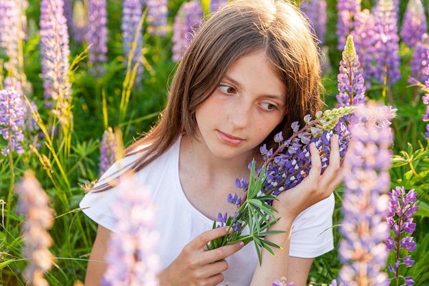 Gelukkig tienermeisje glimlachend buiten mooie jonge tiener vrouw rusten op zomer veld met bloeiende wilde bloemen groene achtergrond gratis gelukkig kind tiener meisje jeugd concept