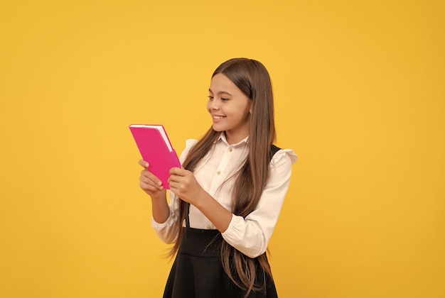 Gelukkig tienermeisje in schooluniform dat boekliteratuur leest