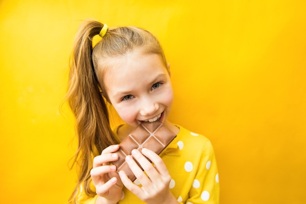 Gelukkig tienermeisje met chocoladereep en mooie glimlach