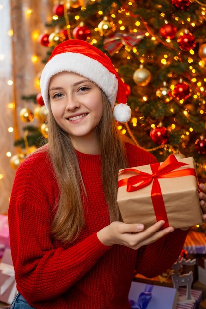 Gelukkig tienermeisje met huidige doos in de buurt van dennenboom van Kerstmis