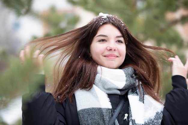 Gelukkig tienermeisje met lang besneeuwd haar in de winter