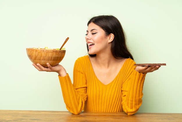 Gelukkig tienermeisje met salade en chocolat