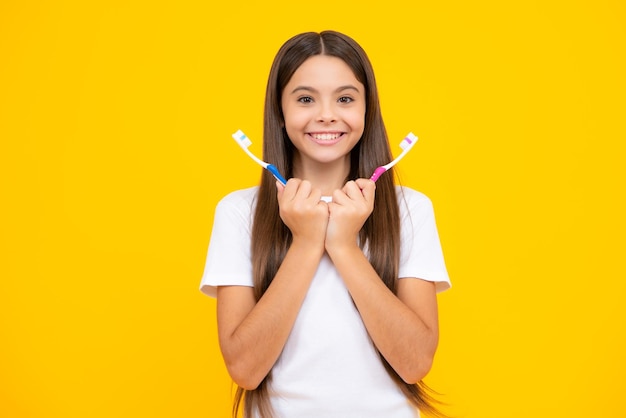 Foto gelukkig tienerportret portret van kaukasisch tienermeisje houdt een tandenborstel die haar tanden poetst ochtendroutine tandhygiëne geïsoleerd op gele achtergrond glimlachend meisje