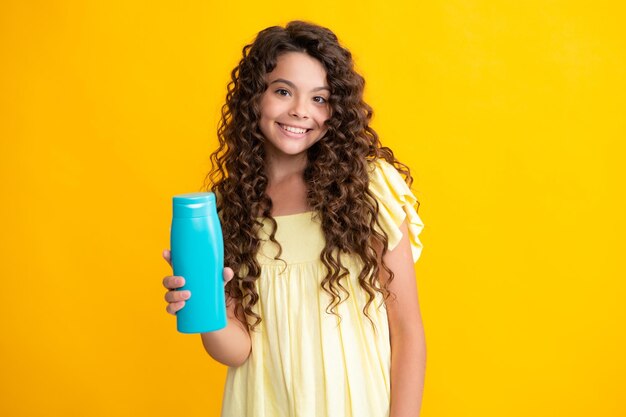 Gelukkig tienerportret van kindmeisje met fles shampoo conditioners of douchegel Kinder haarverzorging Haar cosmetisch product shampoo fles Glimlachend meisje