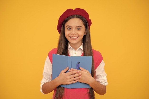 Gelukkig tienerschoolmeisje in Franse baret die aantekeningen maakt in planner-kladblok of notitieboekjeonderwijs