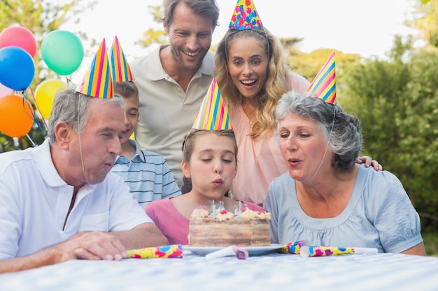 Gelukkig uitgebreid familie lettend meisje die verjaardagskaarsen blazen