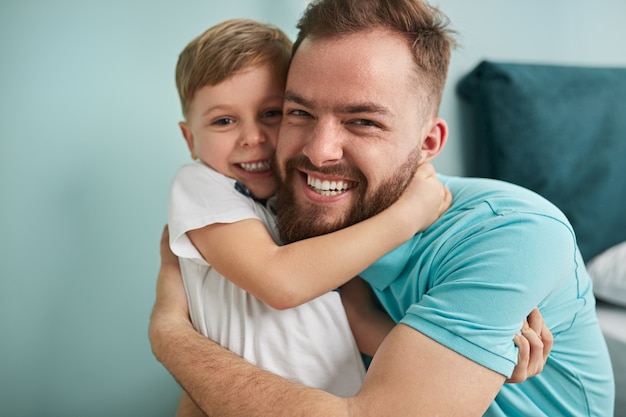 Gelukkig vader en zoontje knuffelen in de slaapkamer