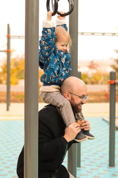 Gelukkig vader spelen met dochtertje op de speelplaats in stadspark. Familie plezier. Familie tijd