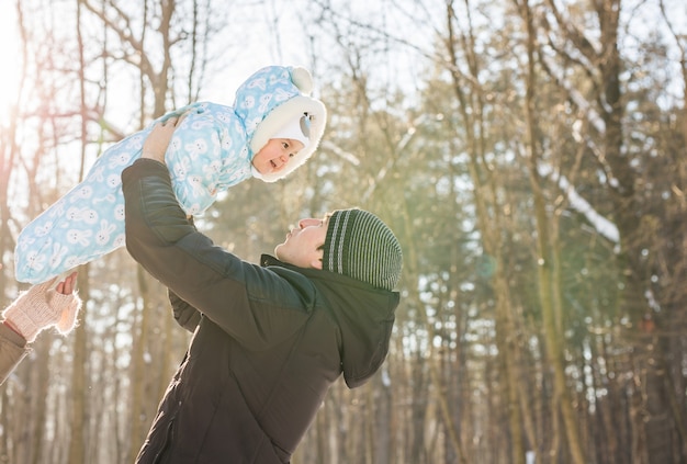 Gelukkig vader spelen met kleine zoon zoon jongen in de winter natuur.