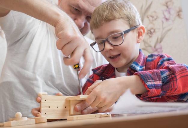 Gelukkig vaderdag- en jeugdconcept vader en zoon in glazen werken met handgereedschap met behulp van