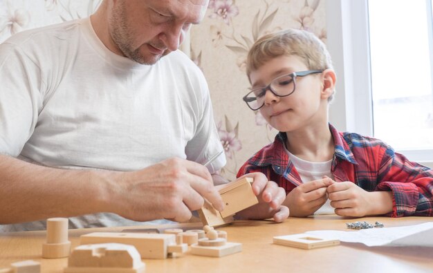 Gelukkig vaderdag- en jeugdconcept Vader en zoon in glazen werken met handgereedschap met behulp van