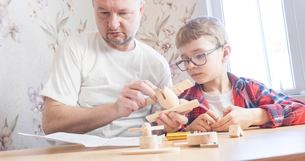 Gelukkig vaderdag- en jeugdconcept vader en zoon in glazen werken met handgereedschap met behulp van