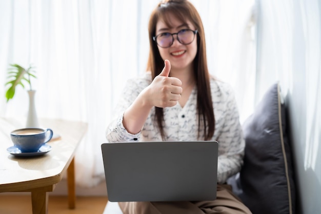 Gelukkig van Aziatische freelance mensen zakelijke vrouwelijke abstracte vervaging met focus Toon duimen opdagen werken met laptopcomputer in coffeeshop zoals het backgroundcommunication concept