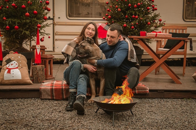 Gelukkig verliefd stel en hun hond brengen samen tijd door op kerstvakantie Cane Corso en zijn eigenaren vieren het nieuwe jaar in de open lucht bij de camper en het vuur