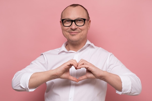 Gelukkig volwassen blanke man in glazen met hartsymbool op roze achtergrond