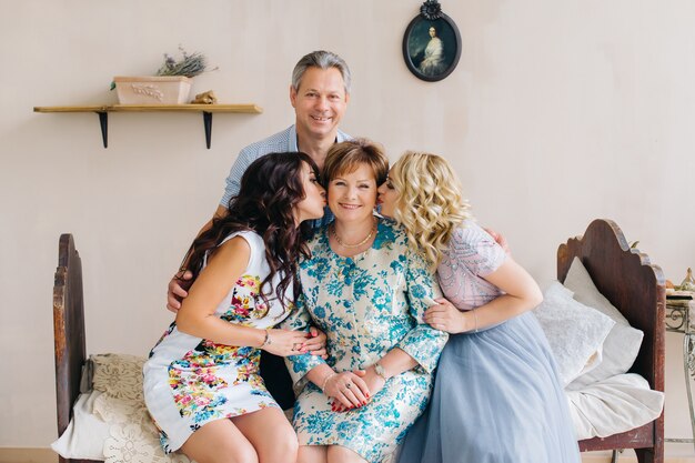 Foto gelukkig volwassen familieportret in vintage interieur. vader, moeder en dochters kussen haar.