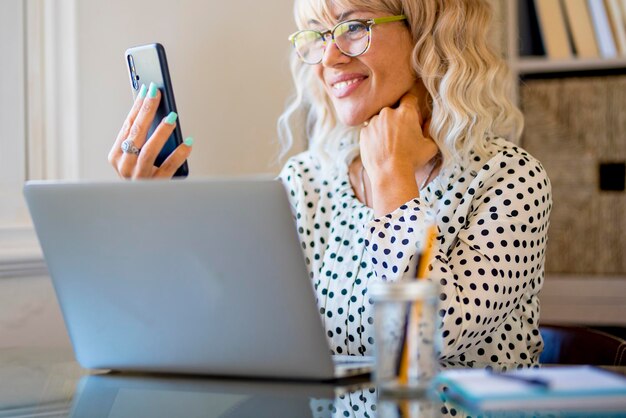 Gelukkig volwassen jonge vrouw professionele zaken doen telefoongesprek conferentie en werken op laptopcomputer - kantoorwerkstation en vrouwelijke mensen slim online werken met mobiel en notebook op bureau