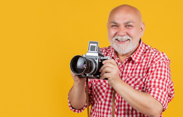 Gelukkig volwassen man met retro fotocamera op gele baqckground