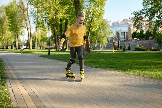 Gelukkig volwassen man rolschaatsen op traject in stadspark