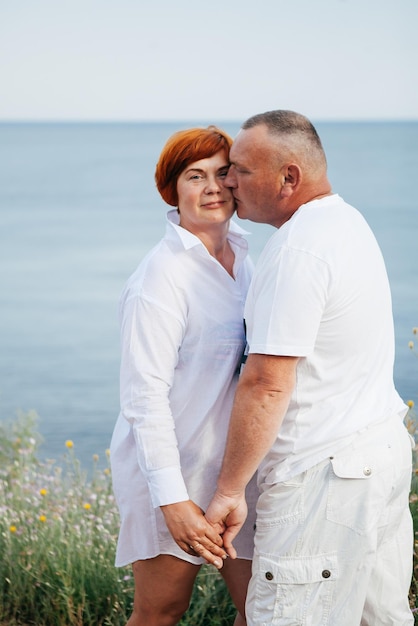 Gelukkig volwassen paar poseren op zonnige dag op het strand