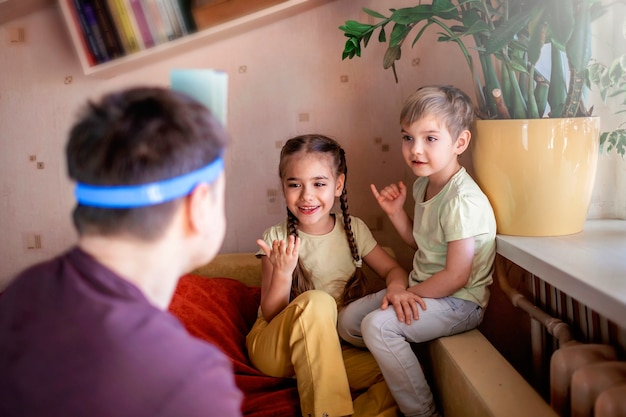 Gelukkig volwassen vader spelen op bordspel met zijn twee kinderen in huiselijk interieur, gezinswaarden eigenlijk, thuis blijven, leven tijdens quarantaine