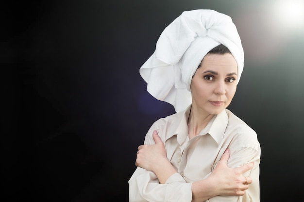 Gelukkig volwassen vrouw met witte handdoek op haar hoofd, zwarte achtergrond.